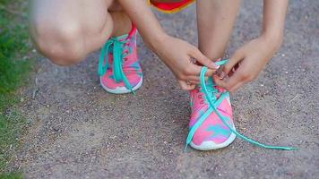 handen van een jong vrouw vetersluiting helder roze en blauw sportschoenen. rennen schoenen - detailopname van vrouw koppelverkoop schoen veters. video