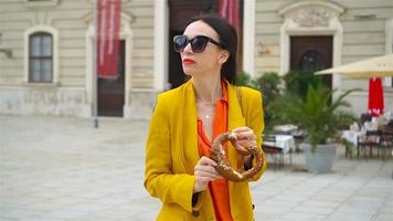 Beautiful young woman holding pretzel and relaxing in park video