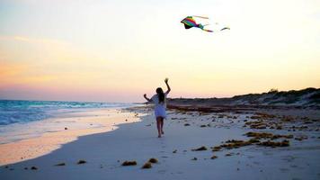 Adorable little girl with flying kite on tropical beach have a lot of fun. Kids play on ocean shore with beach toys video