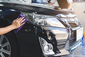 Close up hands of person using microfiber cloth wipe a car after wash the dust and prepare to polish wax. photo