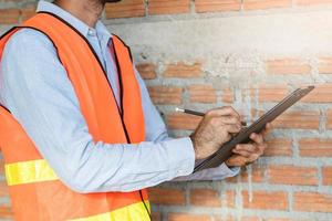 Asian inspector checking structure of new property and taking note in the clipboard for review and fix the house before sell to client photo