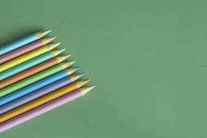 Pastel colored pencils, top view on green background, illustration concept, education and back to school photo