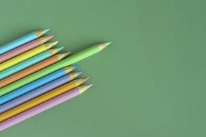 Pastel colored pencils, top view on green background, illustration concept, education and back to school photo