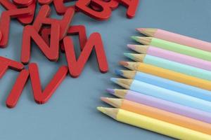Back to school concept with assorted letters and colored pencils in pastel colors photo