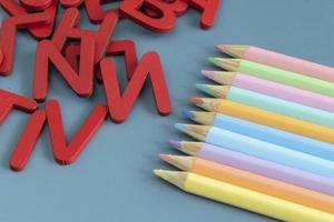 Back to school concept with assorted letters and colored pencils in pastel colors photo