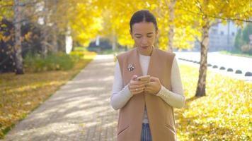 Fall concept - beautiful woman drinking coffee in autumn park under fall foliage video