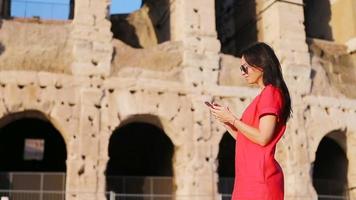 joven mujer en frente de coliseo con inteligente teléfono en manos en Roma, Italia. niña en Europa vacaciones video