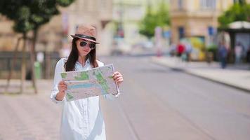 joven turista con un mapa de la ciudad buscando atracción al aire libre. viaje mujer caucásica con mapa afuera durante las vacaciones en europa. video