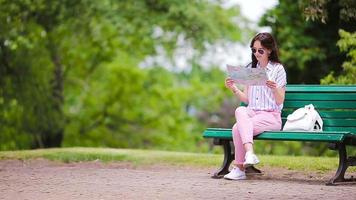 heureuse jeune femme avec un plan de ville en europe. femme touristique de voyage avec carte dans le parc à l'extérieur pendant les vacances video