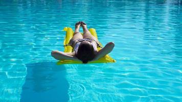 joven mujer relajante con aire colchón en al aire libre nadando piscina