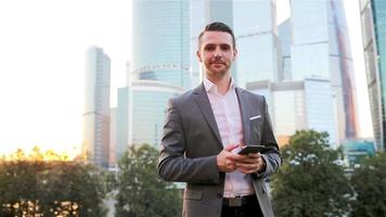 jeune homme caucasien tenant un smartphone pour le travail d'entreprise. video
