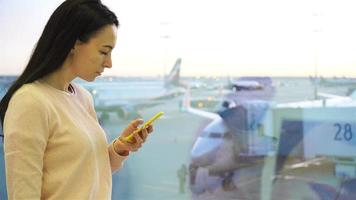 Airline passenger in an airport lounge waiting for flight aircraft. Caucasian woman talk by cellphone near big window background the big plane video