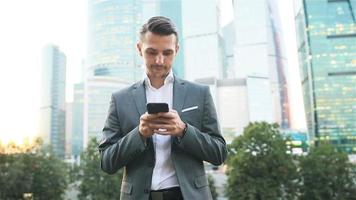 Young caucasian man holding smartphone for business work. video