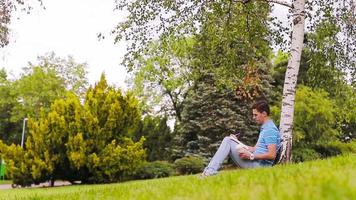 Università alunno studiando per esami all'aperto nel il parco. con lui il suo libri, taccuino, zaino e caffè. video