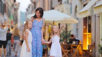 contento madre e poco adorabile ragazze su accogliente strada durante italiano vacanza. famiglia europeo vacanza. video