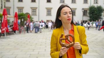 Beautiful young woman holding pretzel and relaxing in park video