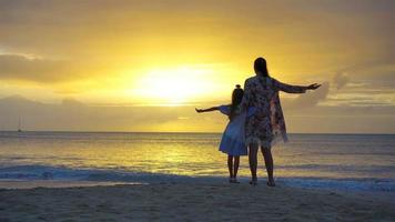 Little girl and happy mother silhouette in the sunset at the beach video