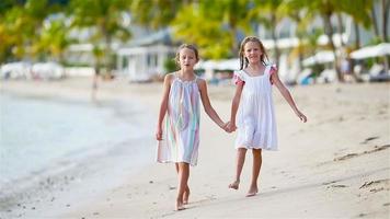 adorable pequeño muchachas caminando en el playa y teniendo divertido juntos video