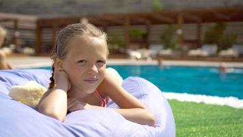 hermosa niña divirtiéndose cerca de una piscina al aire libre