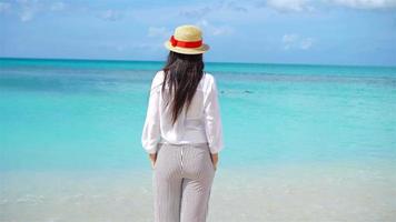 Young beautiful woman having fun on tropical seashore. Happy girl background the blue sky and turquoise water in the sea on caribbean island. video