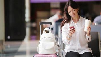 passageiro da companhia aérea em um saguão do aeroporto à espera de aeronaves de voo. mulher caucasiana com smartphone na sala de espera video