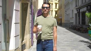 Happy young urban man drinking coffee in european city outdoors video