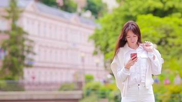 retrato de una mujer hermosa usando un teléfono inteligente al aire libre. video