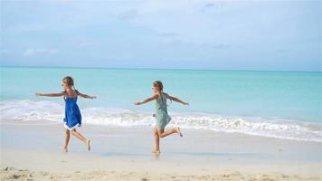 garotinhas engraçadas felizes se divertem muito na praia tropical brincando juntas. câmera lenta video