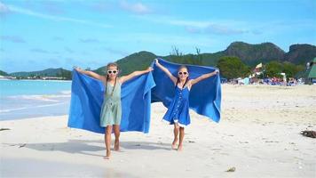 Little happy funny girls have a lot of fun at tropical beach playing together. SLOW MOTION video