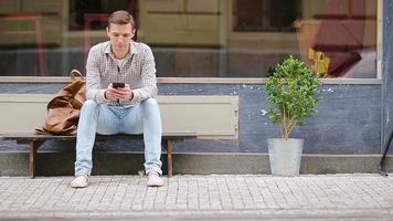 Mann Senden Botschaft durch seine Smartphone draußen auf das Straße. Mann mit Handy, Mobiltelefon Smartphone. video