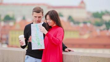 giovane turista coppia in viaggio su vacanze nel Europa sorridente contento. caucasico famiglia con città carta geografica nel ricerca di attrazioni video