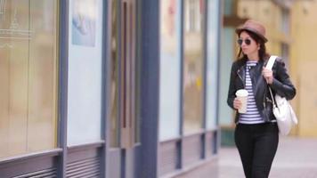 feliz joven mujer urbana tomando café en la ciudad europea. viaje mujer turista con bebida caliente al aire libre durante las vacaciones en europa. video