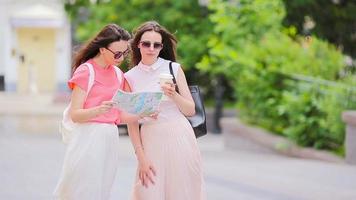 contento giovane donne con shopping borse a piedi lungo città strada. saldi, consumismo e persone concetto. video