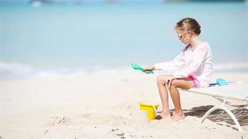 Adorable little girl playing with toys on beach vacation. Kid play with sand video