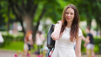 retrato do feliz jovem urbano mulher dentro parque. caucasiano turista apreciar caloroso verão dia ao ar livre. video