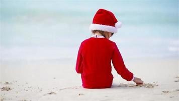 Adorable girl in Christmas hat on white beach during Xmas vacation video