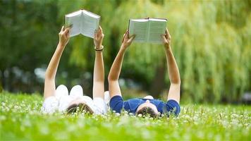 Relaxed young couple reading books while lying on grass video