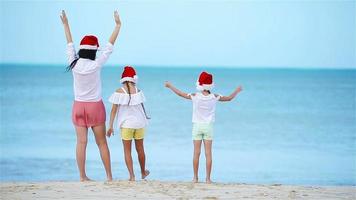 Back view of adorable girl in Christmas hat on white beach during Xmas vacation video