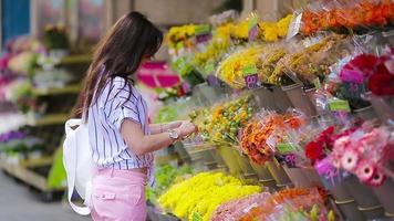 mooi jong vrouw met lang haar- selecteren vers bloemen Bij Europese markt video