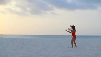 Silhouette of adorable active little girl on white beach at sunset video