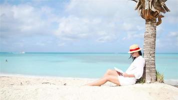 Young woman reading book during tropical white beach video