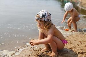 girl on the beach at sea plays with sand with molds photo