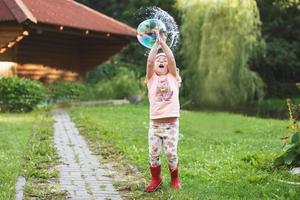 happy girl playing with soap bubbles outdoor. little girl pops a soap bubble photo