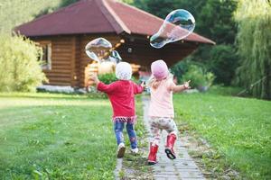 happy girls playing with soap bubbles outdoor. photo