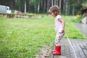 Adorable girl walking with toy at rainy day photo