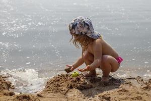 girl on the beach at sea plays with sand with molds photo