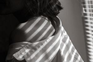 Sensual close up portrait of beautiful young lady relaxing at the window. female shoulder close up. hard shadows. photo