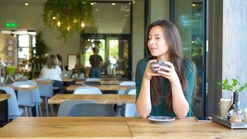 Young woman calling with cell telephone while sitting alone in coffee shop during free time. Attractive female with cute smile having talking conversation with mobile phone while rest in cafe video