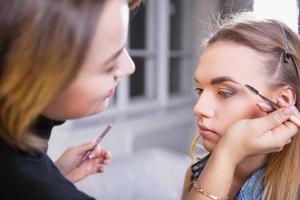 Makeup artist applying make up on alluring model photo