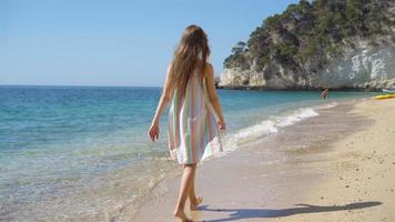 skön liten flicka i klänning på strand har roligt. rolig flicka njut av sommar semester. video